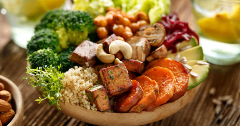 Healthy vegan dish with fried tofu, sweet potatoes, quinoa, broccoli, cashew nuts, mushrooms, avocado, and chickpeas