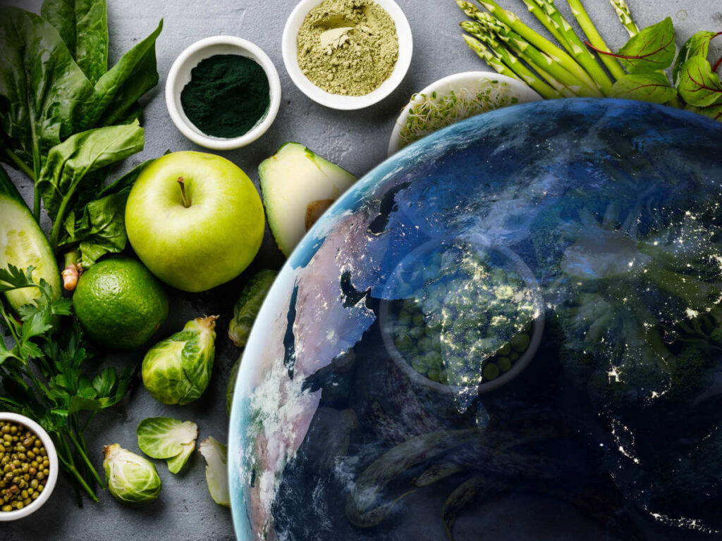 Satellite image of Earth in front of a variety of green vegan food, including apple, avocado, live, spinach, and lentils