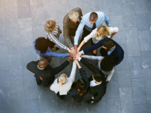 Diverse group of employees putting hands together to team up for corporate responsibility and sustainability initiatives