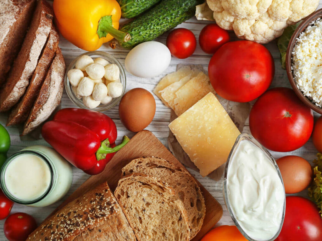 Non-vegan ingredients like eggs, milk, and cheese lying on a table between plant-based ingredients and bread